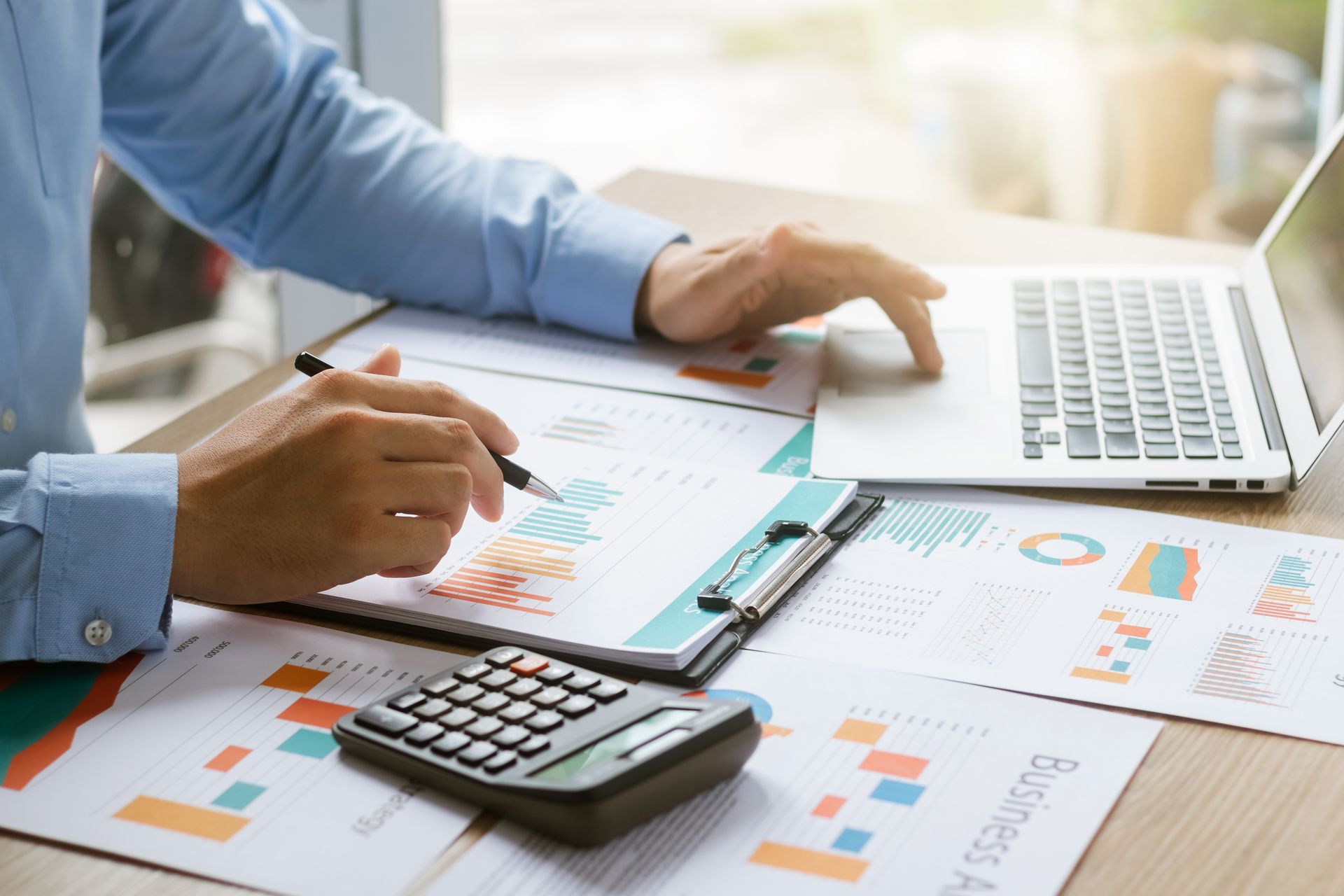 Small business cash flow estimate analysis with financial charts, calculator, and laptop.