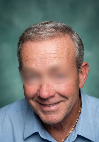 Portrait of a smiling man in a blue shirt against a soft green background