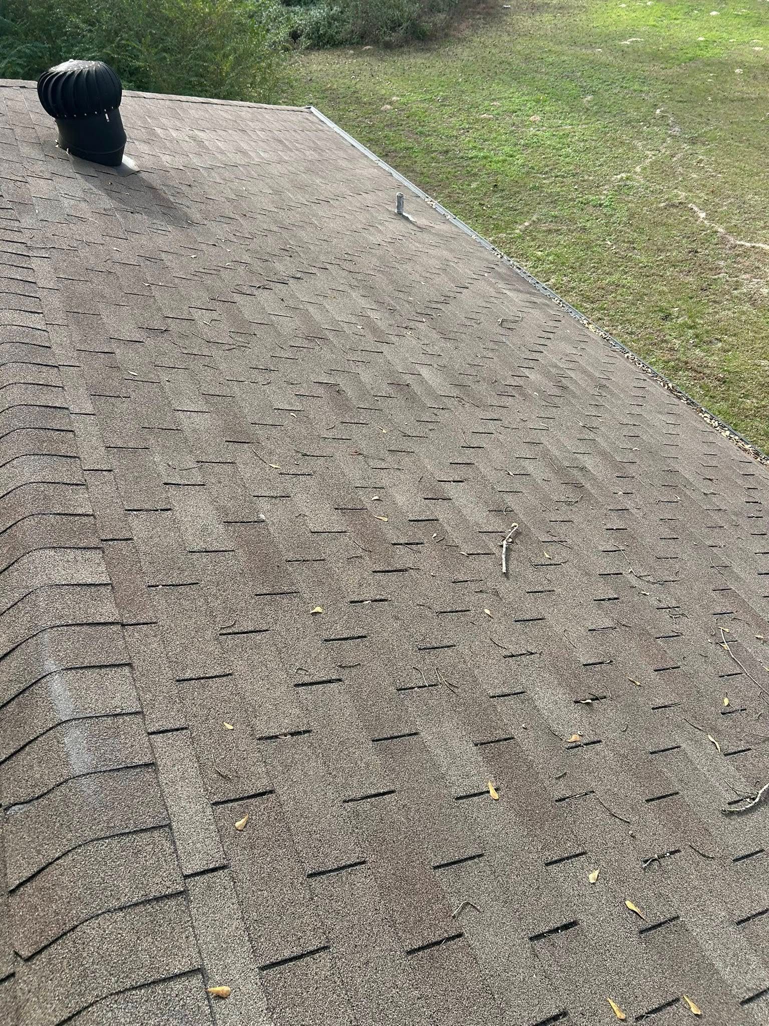 Asphalt shingle roof with visible wear and tear, and a black vent pipe.