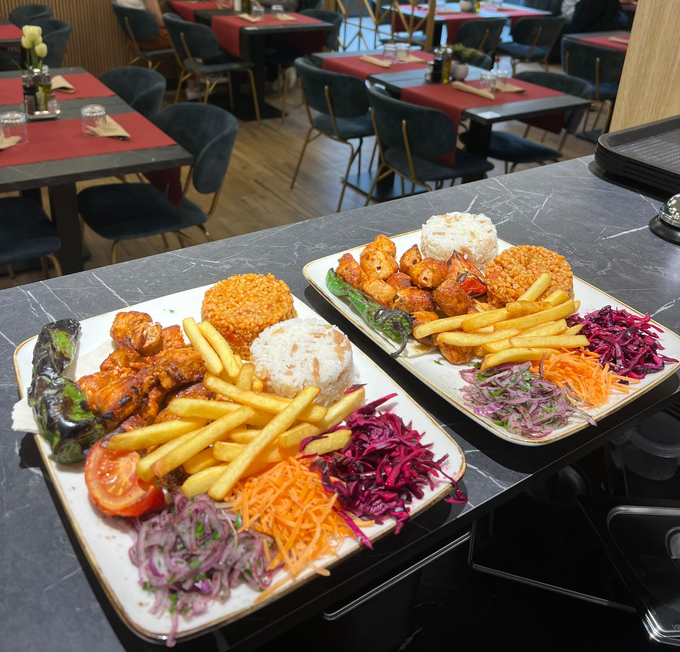 Due piatti di fritti con patatine fritte e insalata su un tavolo di ristorante con decorazioni rosse e nere.