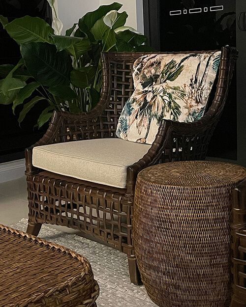 Wicker Patio Chair With Cream Cushion and Leafy Pillow Beside a Woven Ottoman and Potted Plant — Tropic Living in Trinity Beach, QLD