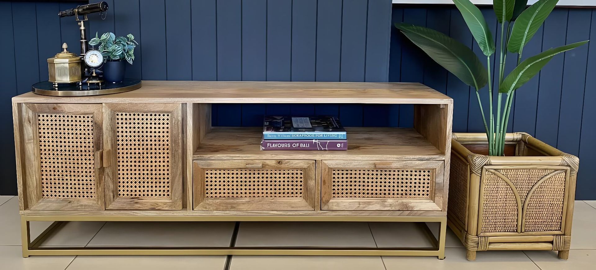 Woven Rattan TV Console With Shelves and Decor Against a Dark Blue Wall, Beside a Potted Plant and Matching Side Table — Tropic Living in Smithfield, QLD