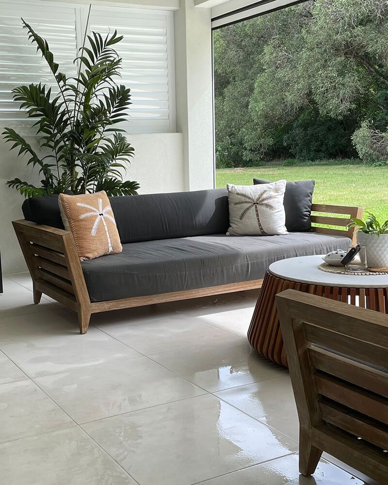 Modern Patio with Wooden Sofa, Round Table, Potted Plant, and Garden View — Tropic Living in Smithfield, QLD