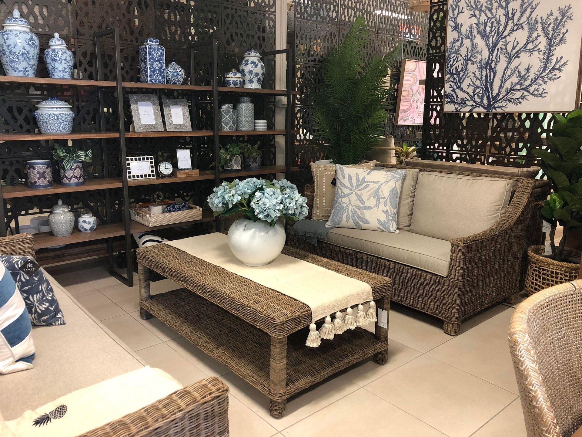 Outdoor Patio Seating Area With Wicker Sofa, Coffee Table, and Shelves of Decorative Pottery and Plants — Tropic Living in Mossman, QLD