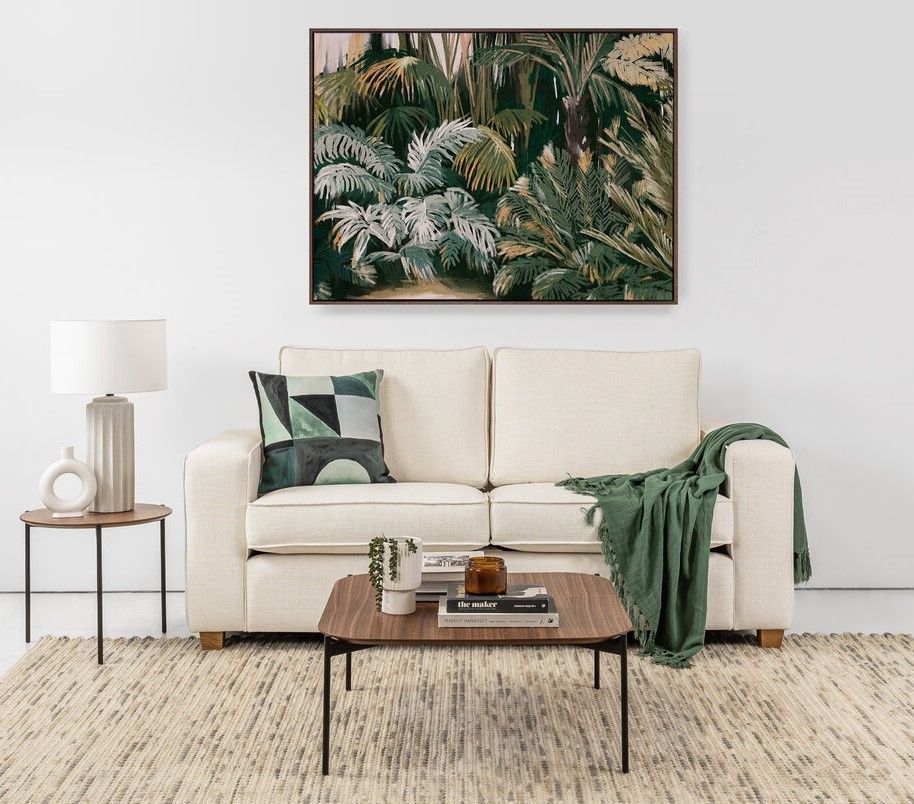Modern Living Room With Cream Sofa, Leafy Wall Art, Wooden Coffee Table, Lamp, And Green Throw Blanket — Tropic Living in Clifton Beach, QLD