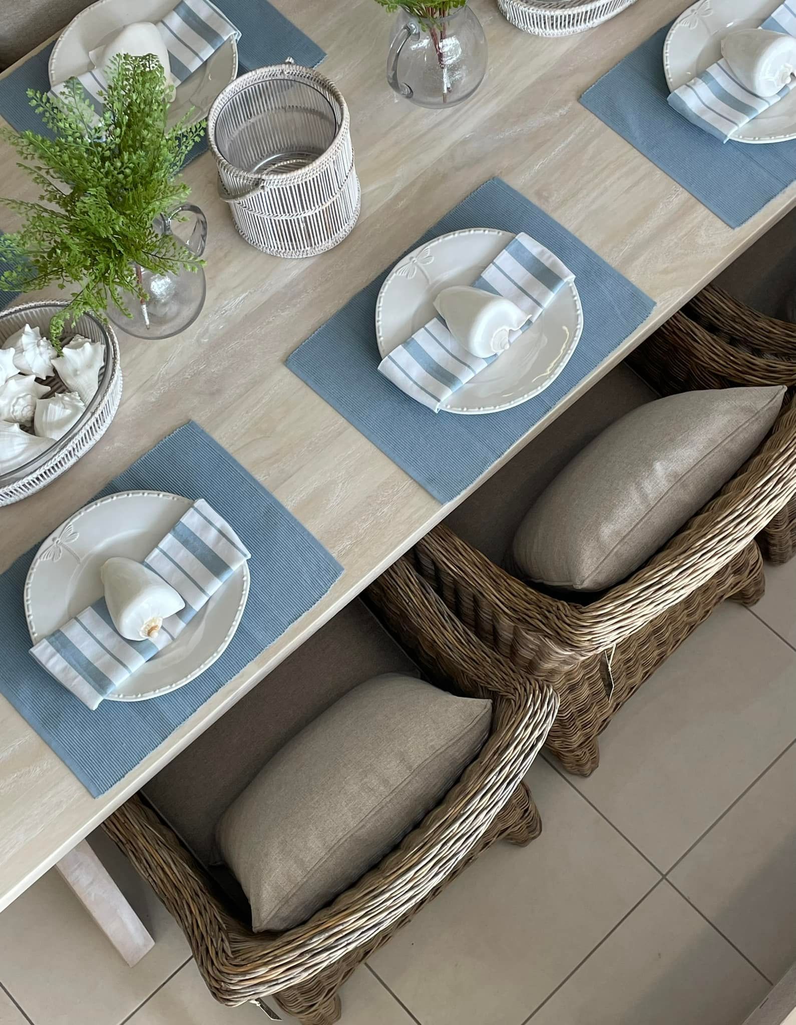 Set Dining Table With Blue Placemats, White Dishes, and Woven Chairs on a Tiled Floor — Tropic Living in Kewarra Beach, QLD