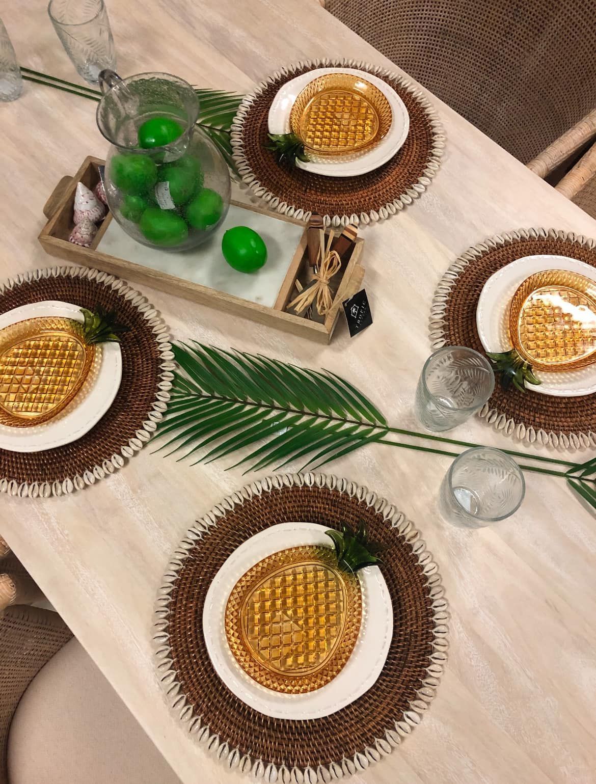 Overhead View of a Table Set With Decorative Plates, Green Glass Bottles, and Palm Leaves — Tropic Living in Smithfield, QLD