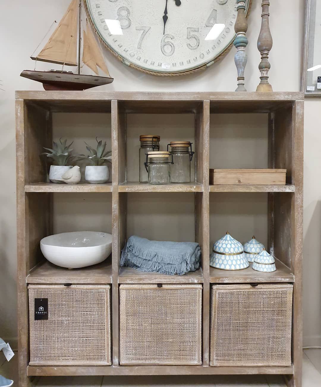 Wooden Cubby Shelf With Decor: Potted Plants, Jars, Bowl, Blue Cloth, Woven Boxes, Model Sailboat, and Wall Clock — Tropic Living in Port Douglas, QLD