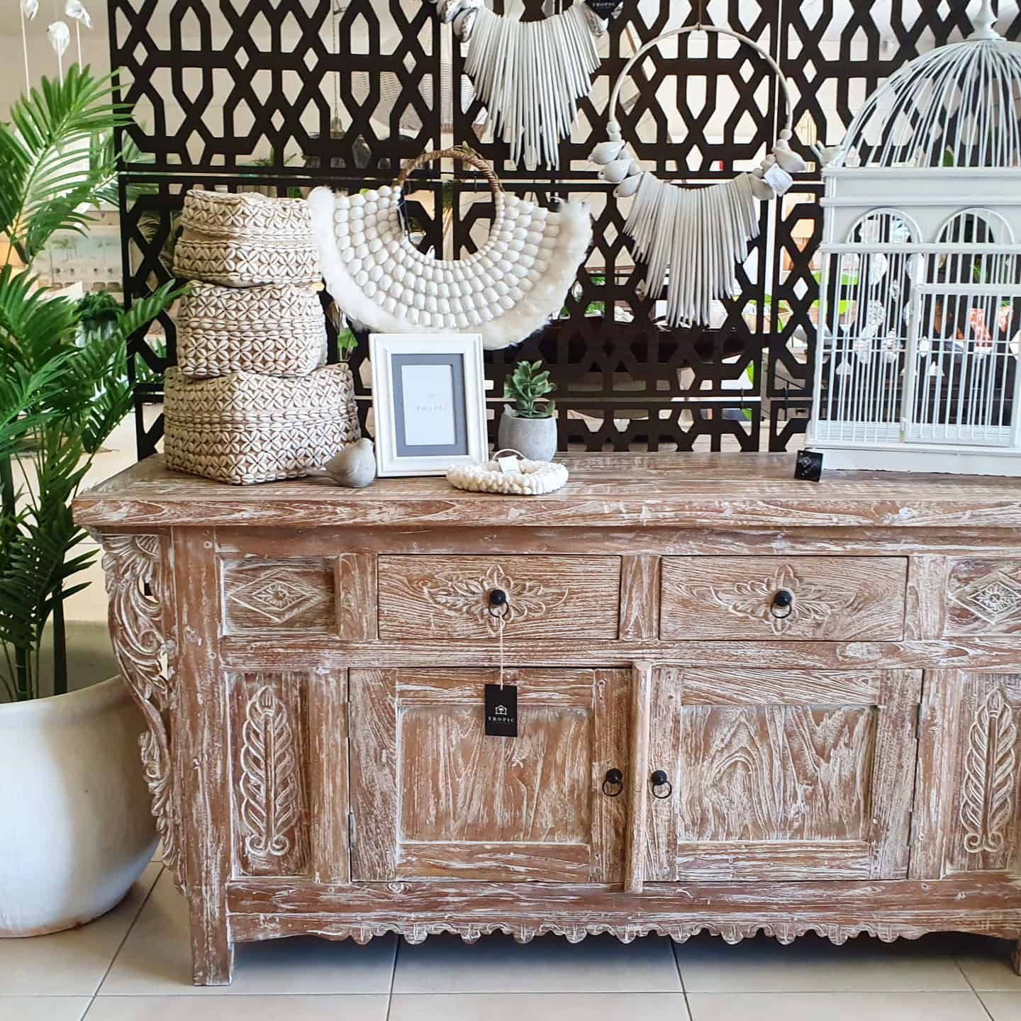 Decorative Wooden Sideboard With Framed Art, White Accents, and a Potted Plant in a Bright Interior — Tropic Living in Smithfield, QLD