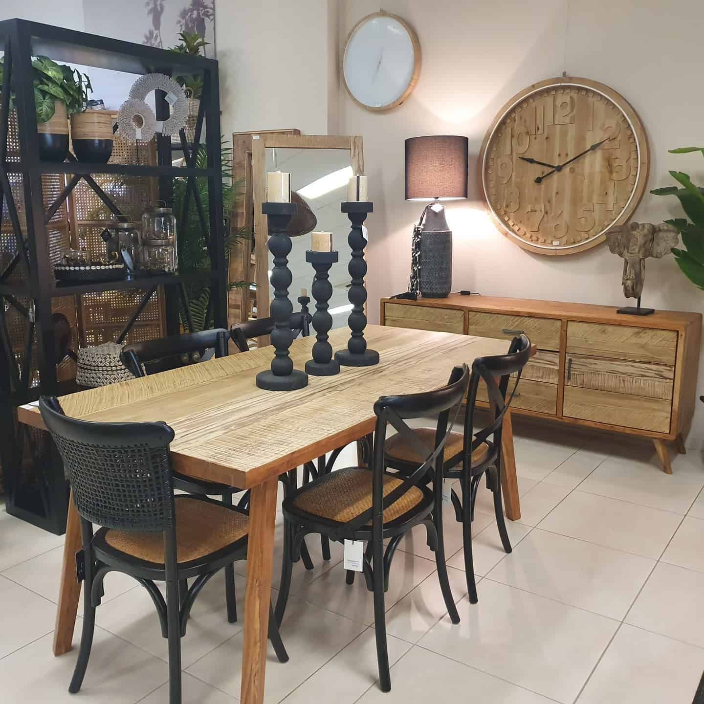 Cozy Dining Room With a Wooden Table, Black Chairs, Large Wall Clock, and Decorative Shelving — Tropic Living in Smithfield, QLD