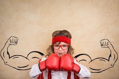 Child in red boxing gloves and headband, posing with drawn flexing arms on a beige background.
