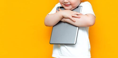 Person in a white shirt hugging a gray laptop against a bright yellow background