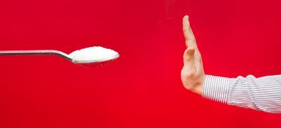 A spoon with white powder faces a raised hand on a red background