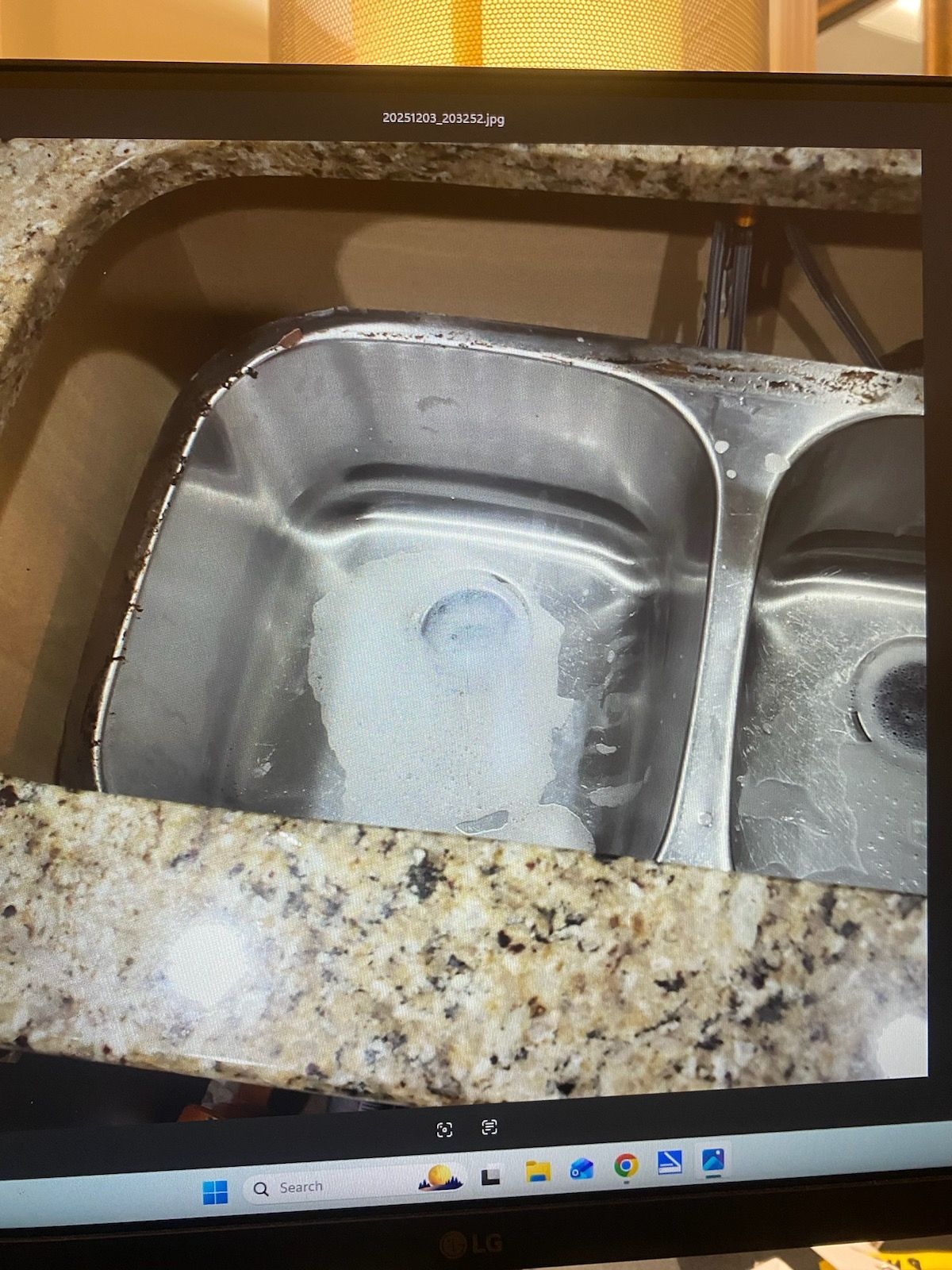 Stainless steel double sink in a speckled granite countertop. A roll of paper towels sits in the left basin.