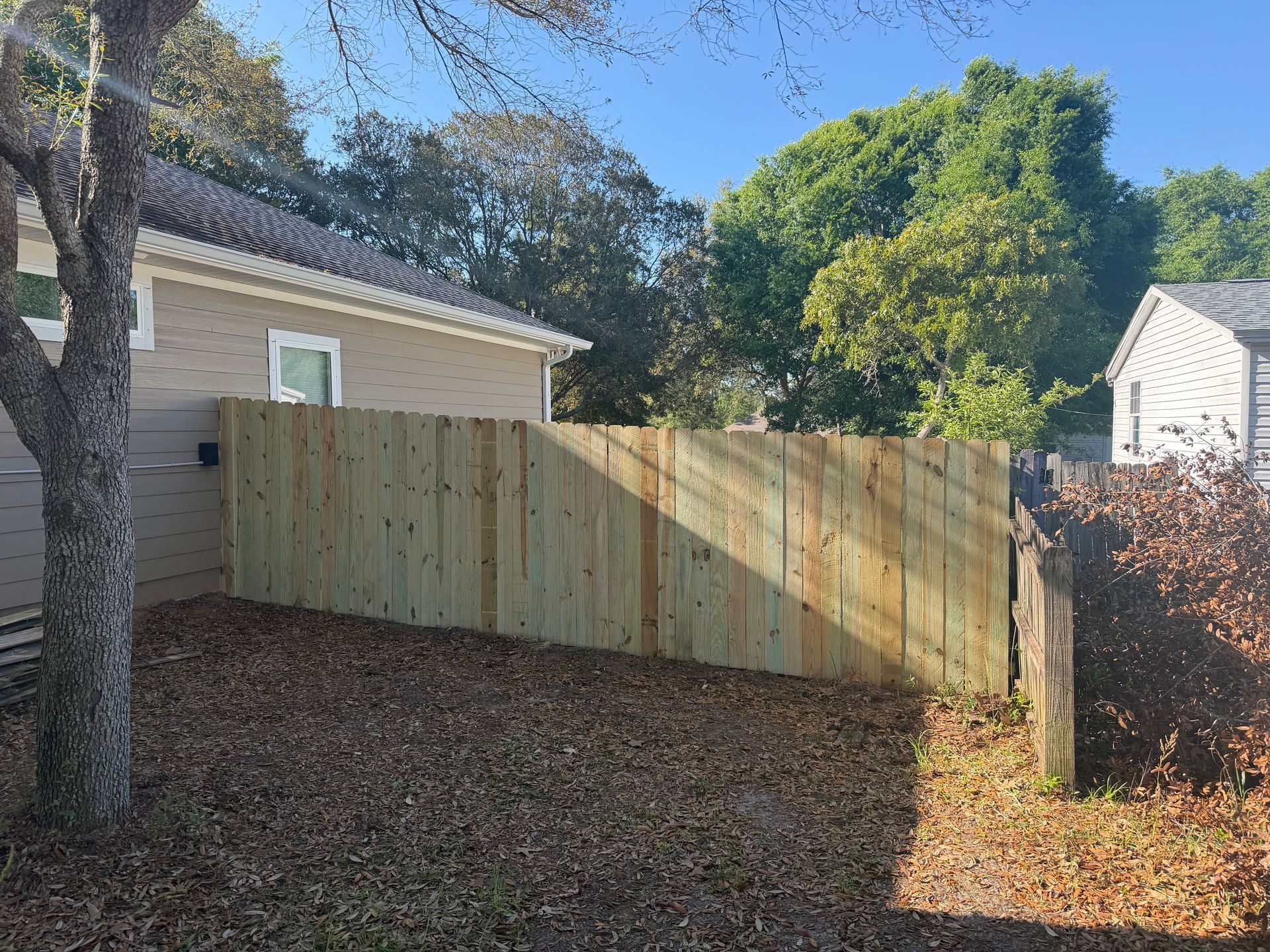 Wooden fence next to a red brick building, with a cloudy sky in the background.
