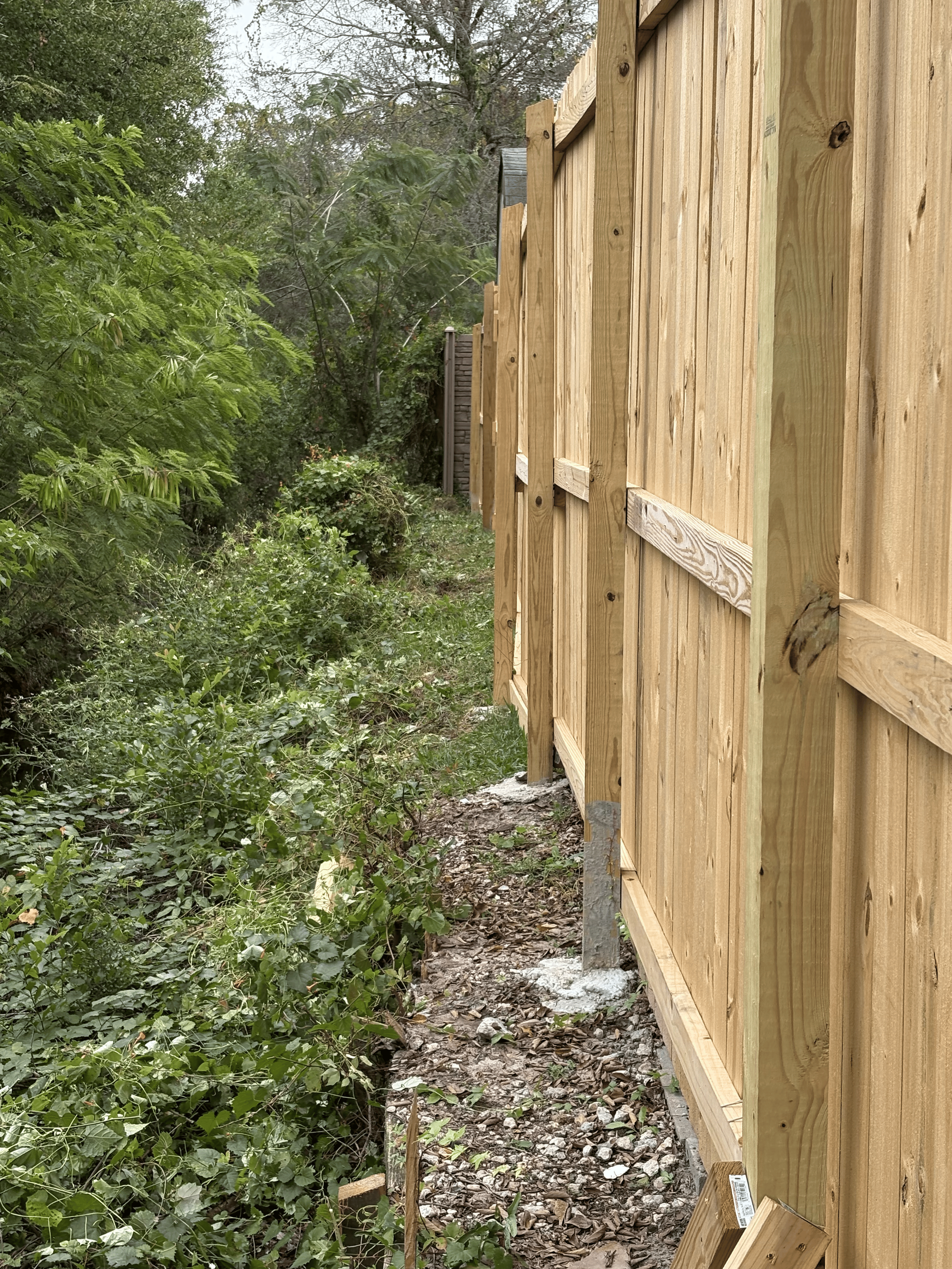 Wooden fence bordering a lush green area.