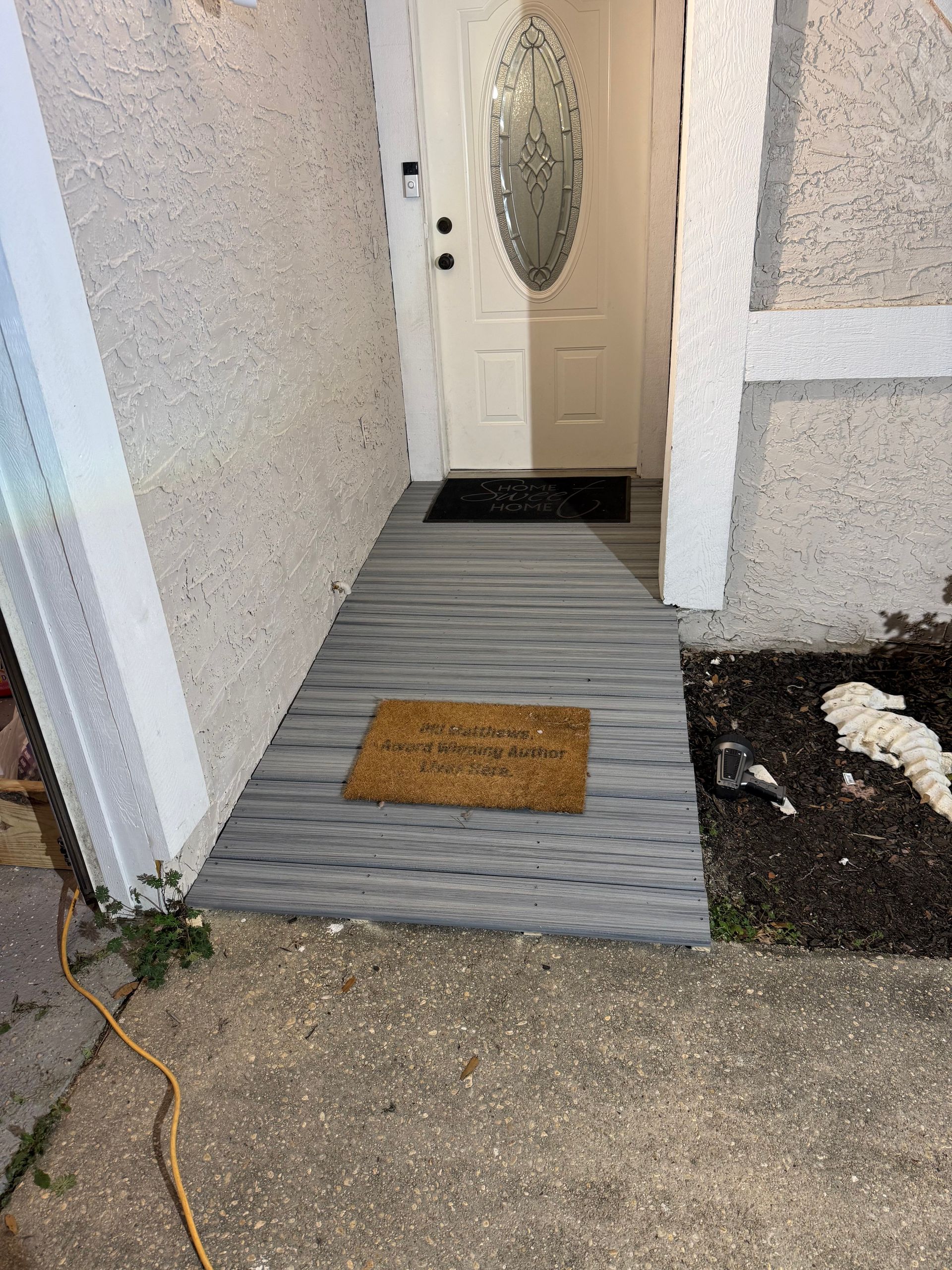 Entryway with light gray patterned walkway leading to a white door. A doormat is visible.
