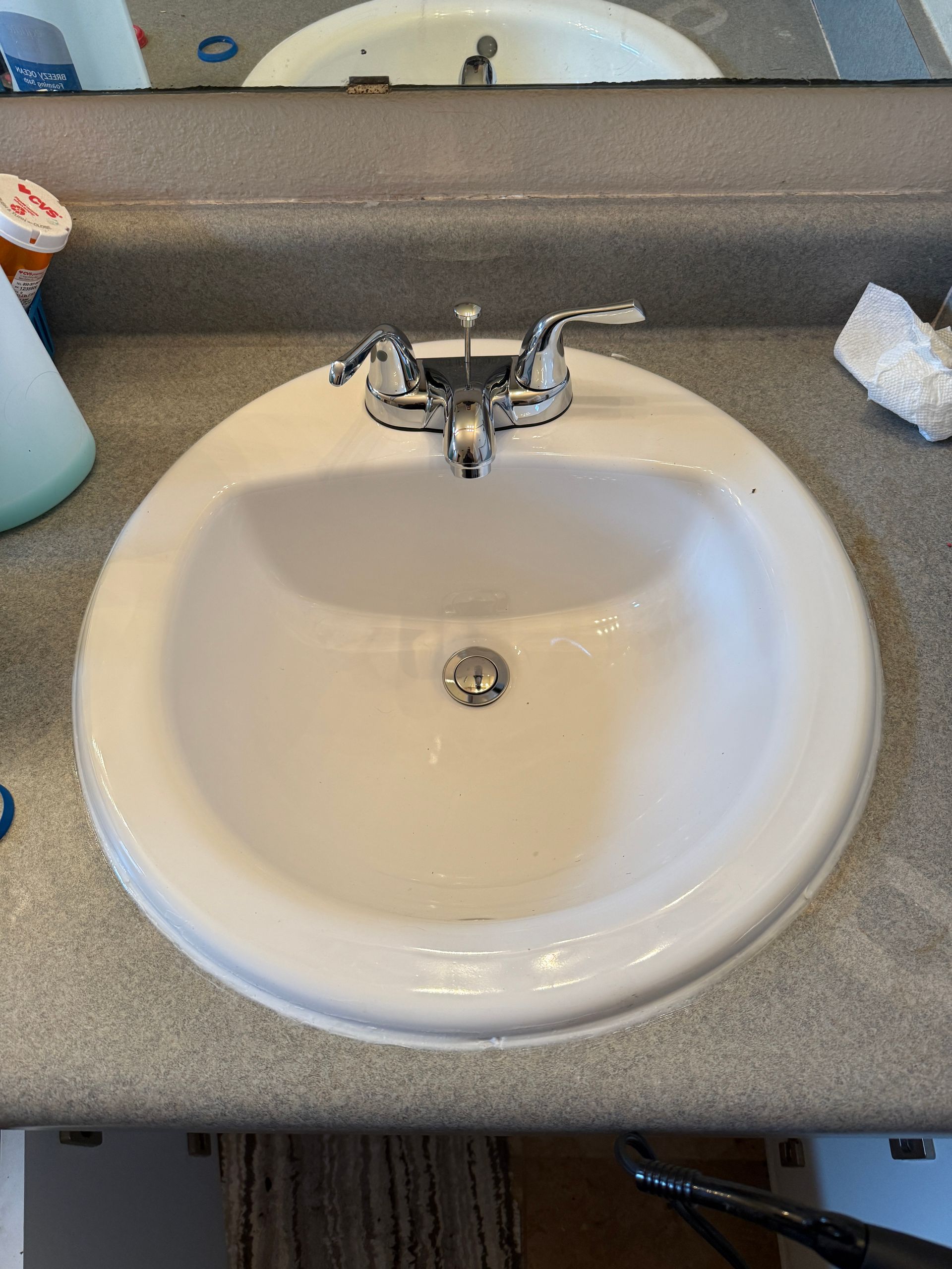 White oval bathroom sink with chrome faucet on a gray countertop.