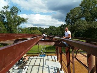 Workers installing steel beams on a bridge frame under construction outdoors