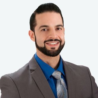 Smiling man in gray suit and blue shirt on white background