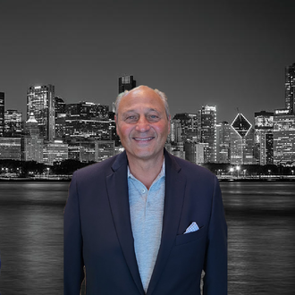 Smiling man in a navy blazer before a black-and-white city skyline at night
