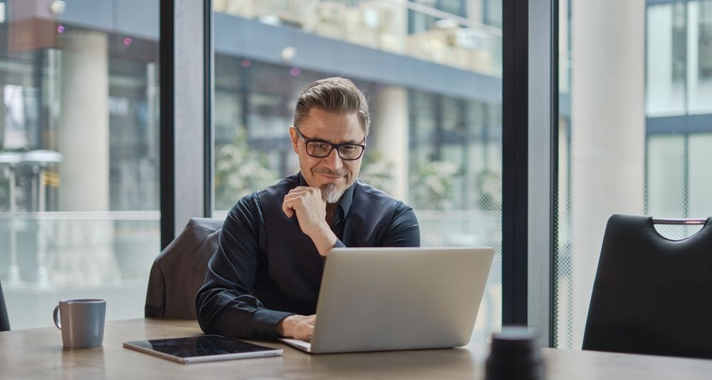 A man is sitting at a table using a laptop computer.