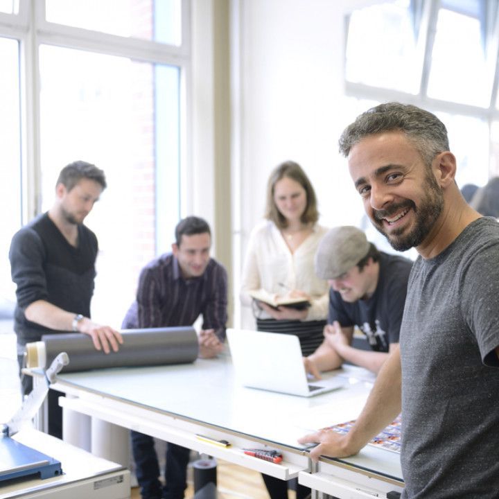A group of people are sitting around a table with a laptop on it