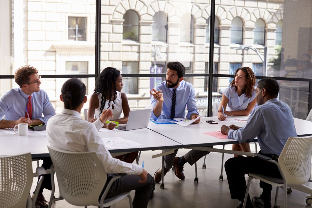 A group of business people are sitting around a table having a meeting.