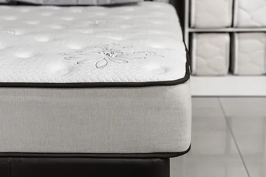 Close-up of a mattress with white tufted top, gray sides, and black trim.