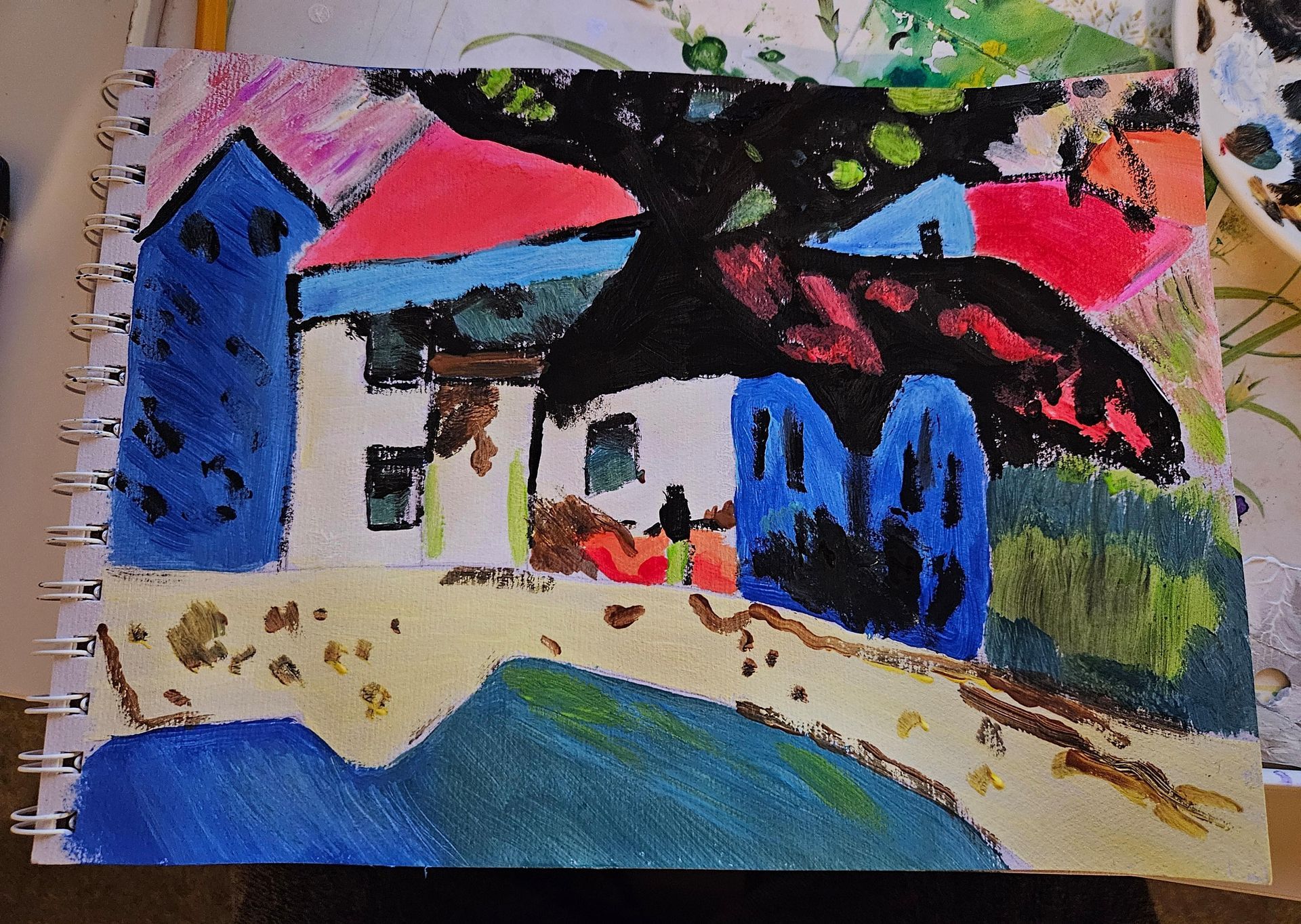 Colorful childlike painting of houses with a blue tree, red roof, and blue water in the foreground