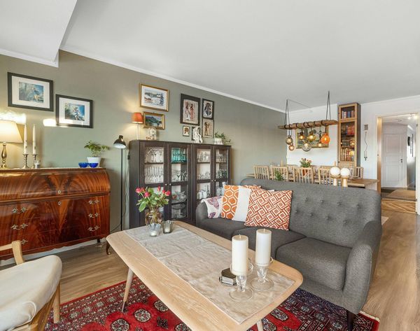Cozy living room with gray sofa, coffee table, red rug, and wooden cabinets along the wall Cozy living room with gray sofa, coffee table, red rug, and wooden cabinets along the wall