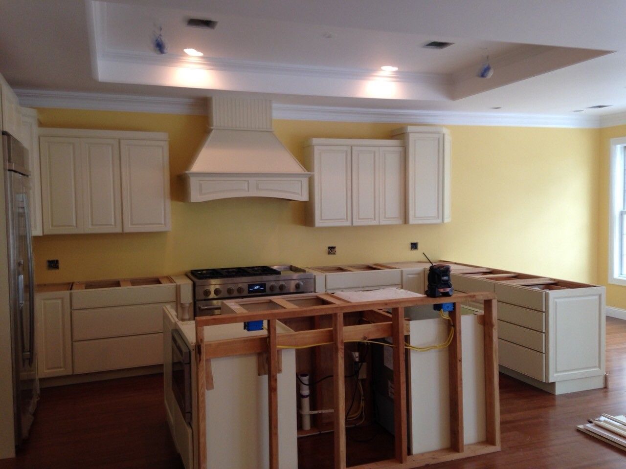 Partially renovated kitchen with white cabinets, yellow walls, and a central island frame under construction
