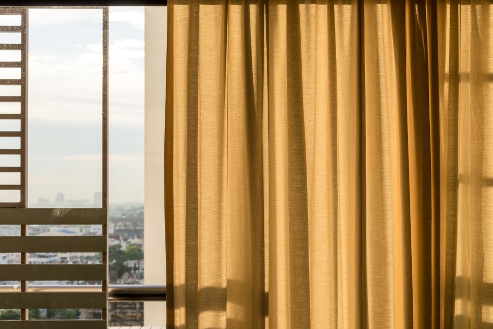 A Window with Yellow Curtains and A View of The City — Phoenix Blinds In Albion Park, NSW