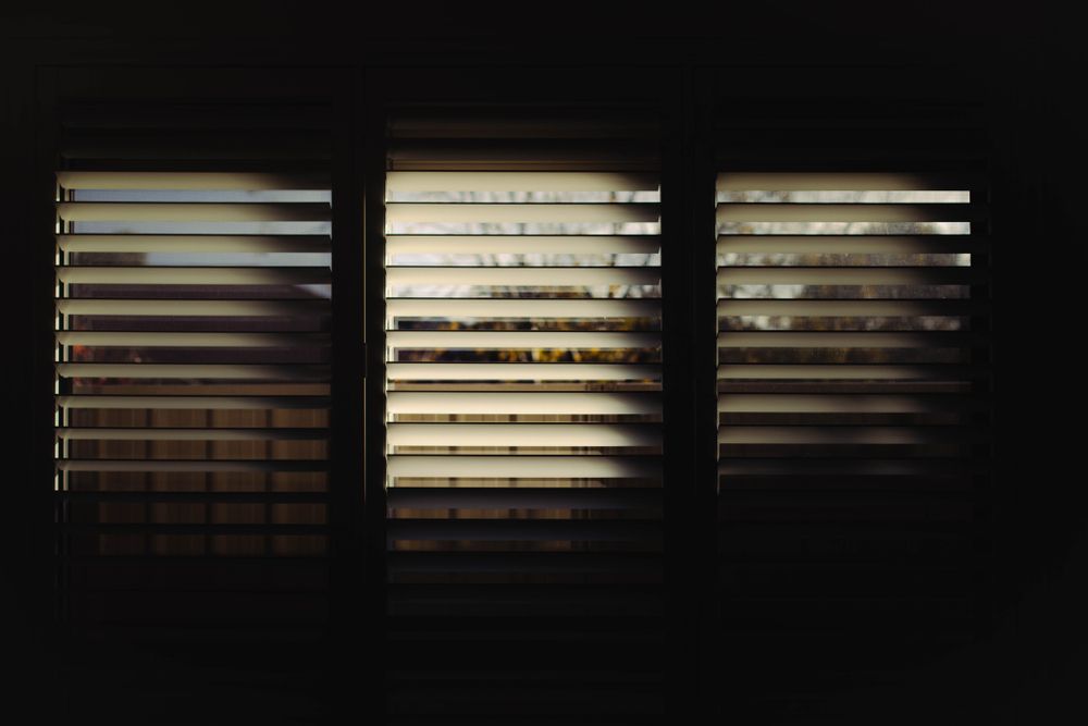 The sun is shining through the blinds of a window — Phoenix Blinds In Albion Park, NSW