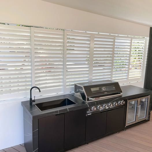 A kitchen with a grill , sink and shutters on the windows. — Phoenix Blinds In Albion Park Rail, NSW
