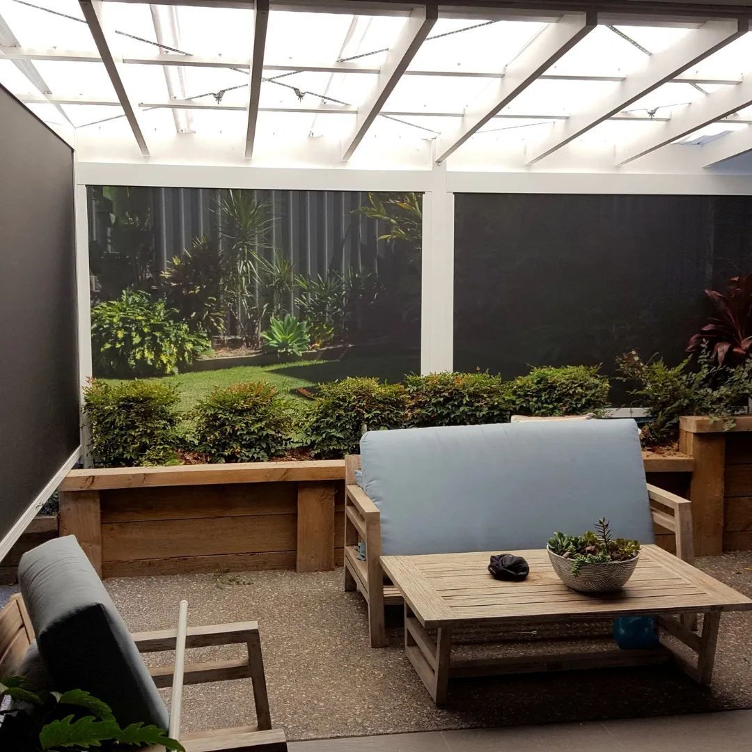 A patio with a couch and a table with a picture of a garden on the wall — Phoenix Blinds In Albion Park Rail, NSW