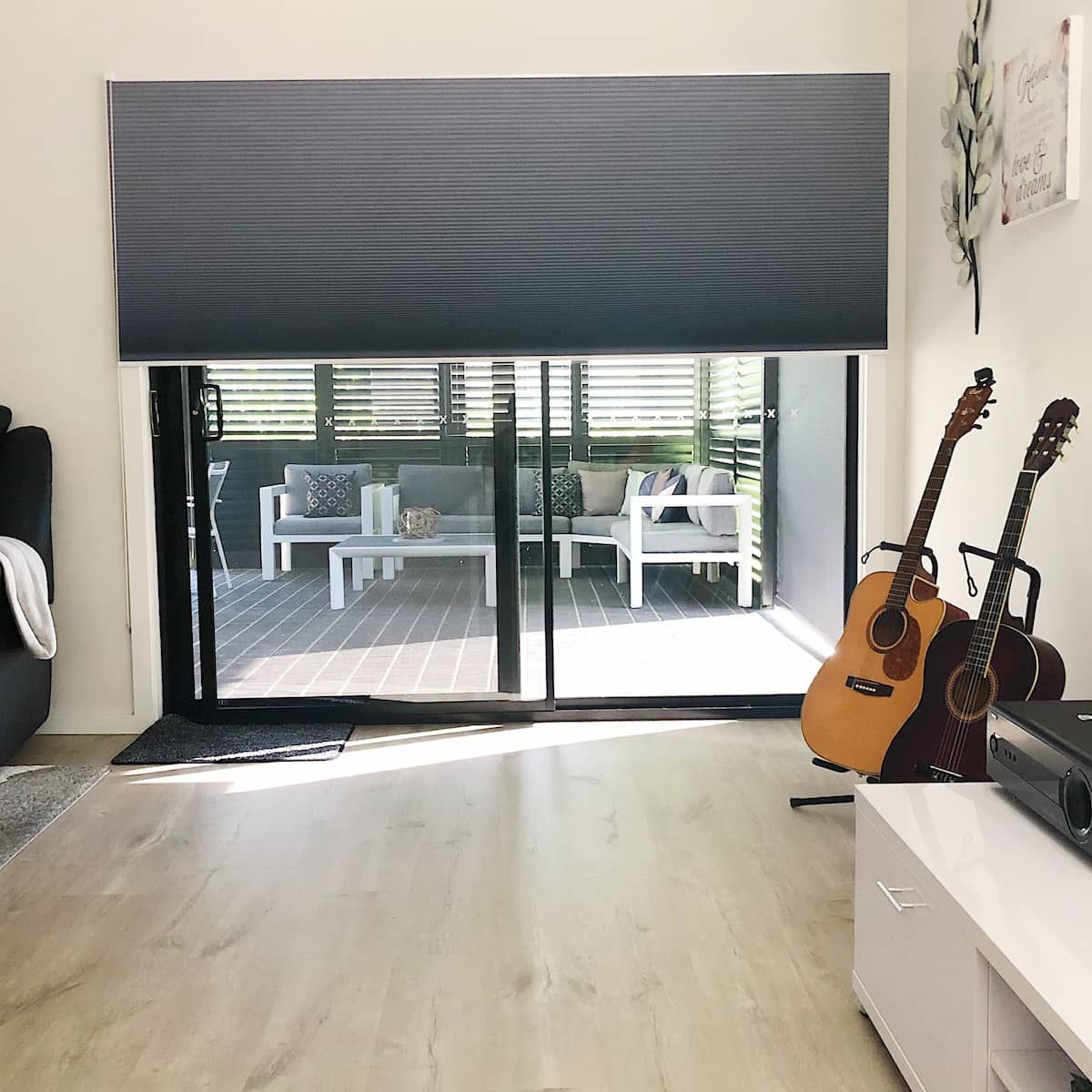 A Living Room with Two Guitars in Front of A Sliding Glass Door — Phoenix Blinds In Albion Park Rail, NSW