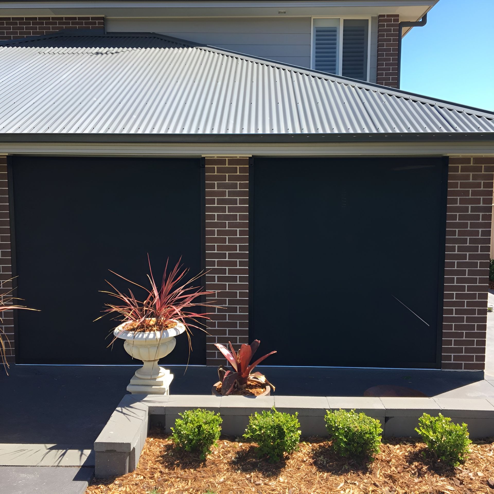 Two Windows on A Brick Building with Black Roller Shutters — Phoenix Blinds In Dapto, NSW