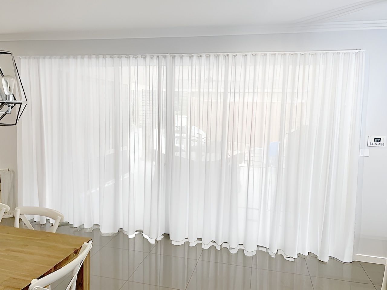 A Dining Room with A Wooden Table and Chairs and White Curtains — Phoenix Blinds In Shellharbour, NSW