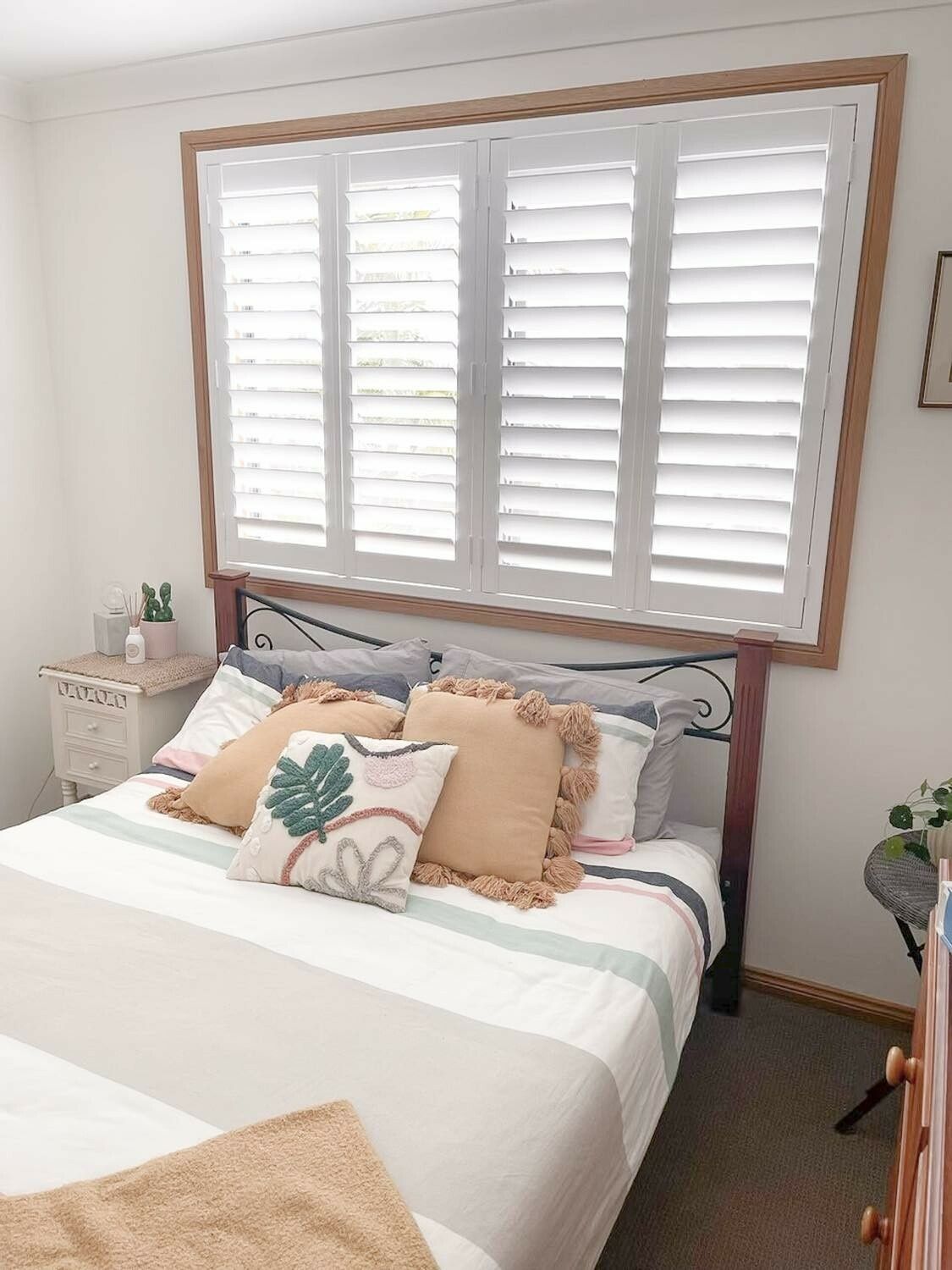 A Bedroom with A Bed and A Window with Shutters — Phoenix Blinds In Shellharbour, NSW