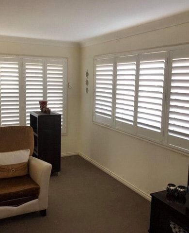 A Living Room with A Couch, Chair and Shutters on The Windows — Phoenix Blinds In Albion Park Rail, NSW