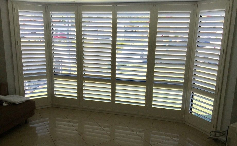 A Living Room with White Shutters on The Windows and A Couch — Phoenix Blinds In Albion Park Rail, NSW
