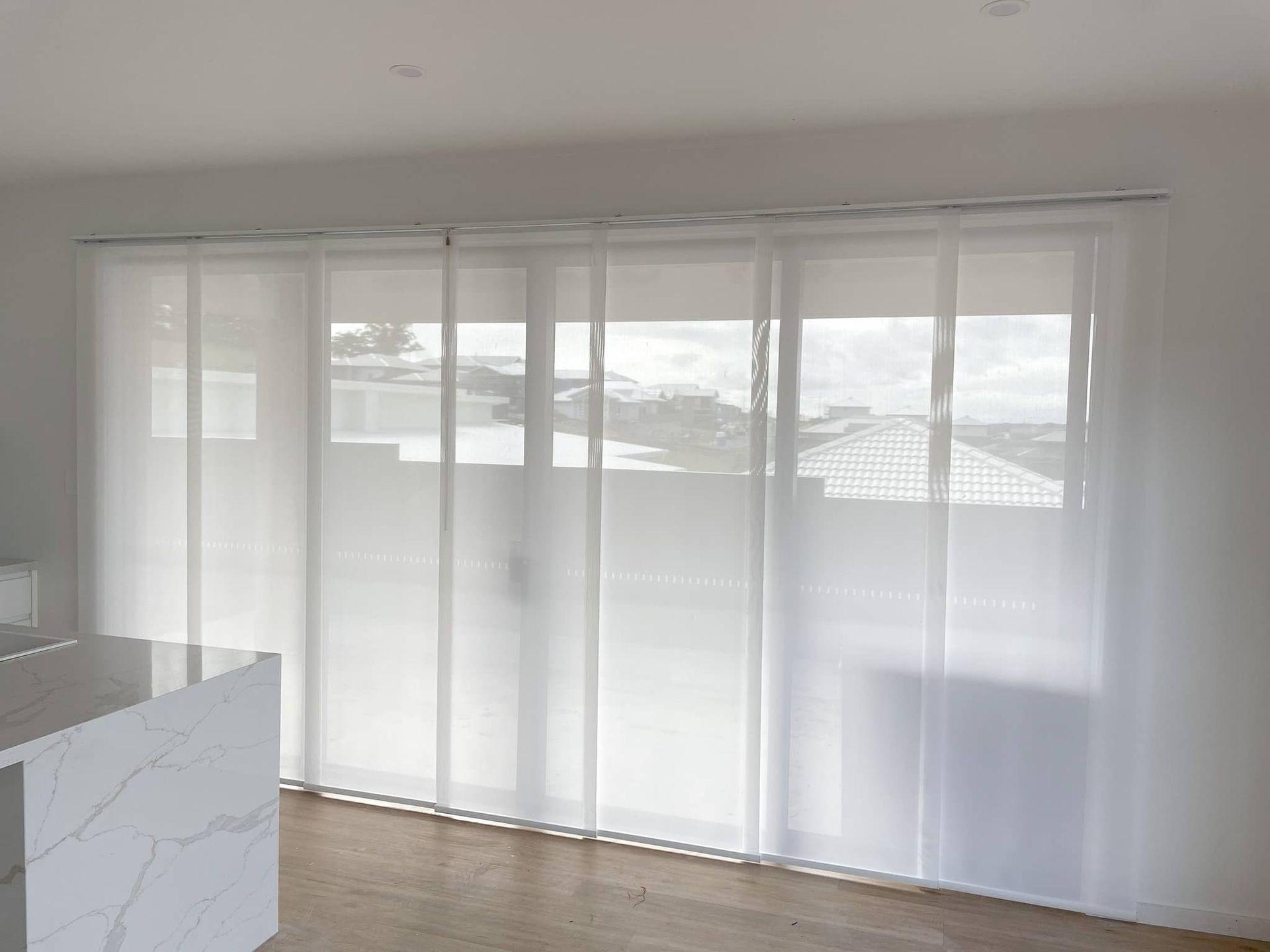 A Living Room with A Sliding Glass Door and White Blinds — Phoenix Blinds In Albion Park, Rail