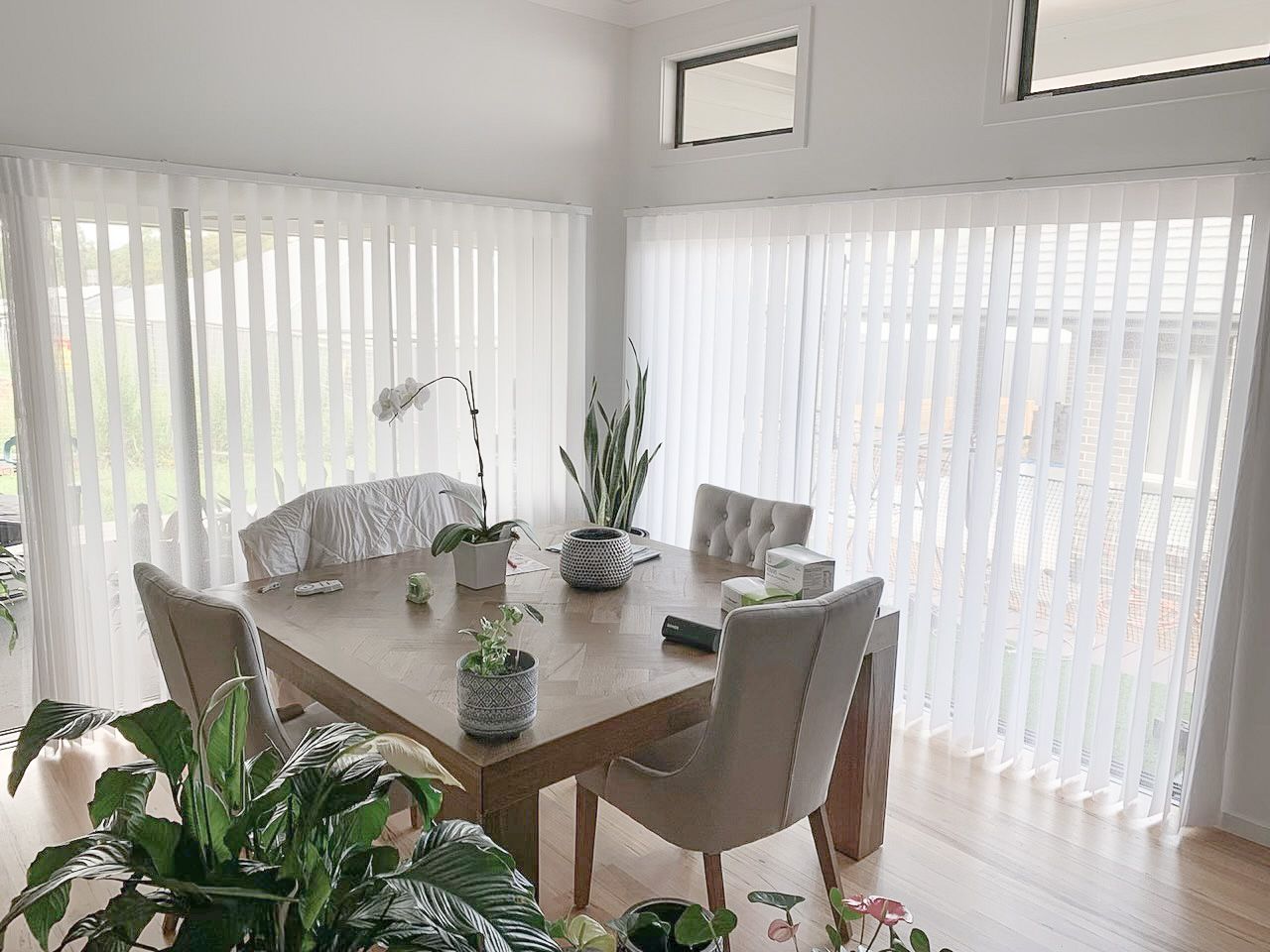 A Dining Room with A Table and Chairs and White Vertical Blinds — Phoenix Blinds In Albion Park Rail, NSW
