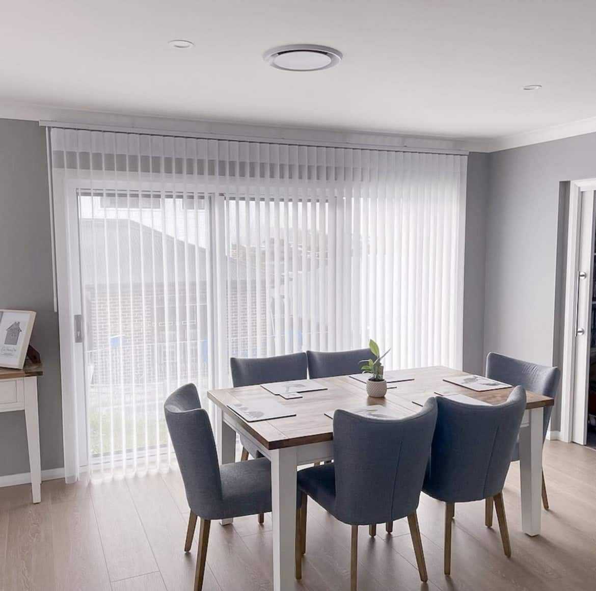 A Dining Room with A Table and Chairs and Sliding Glass Doors — Phoenix Blinds In Albion Park Rail, NSW
