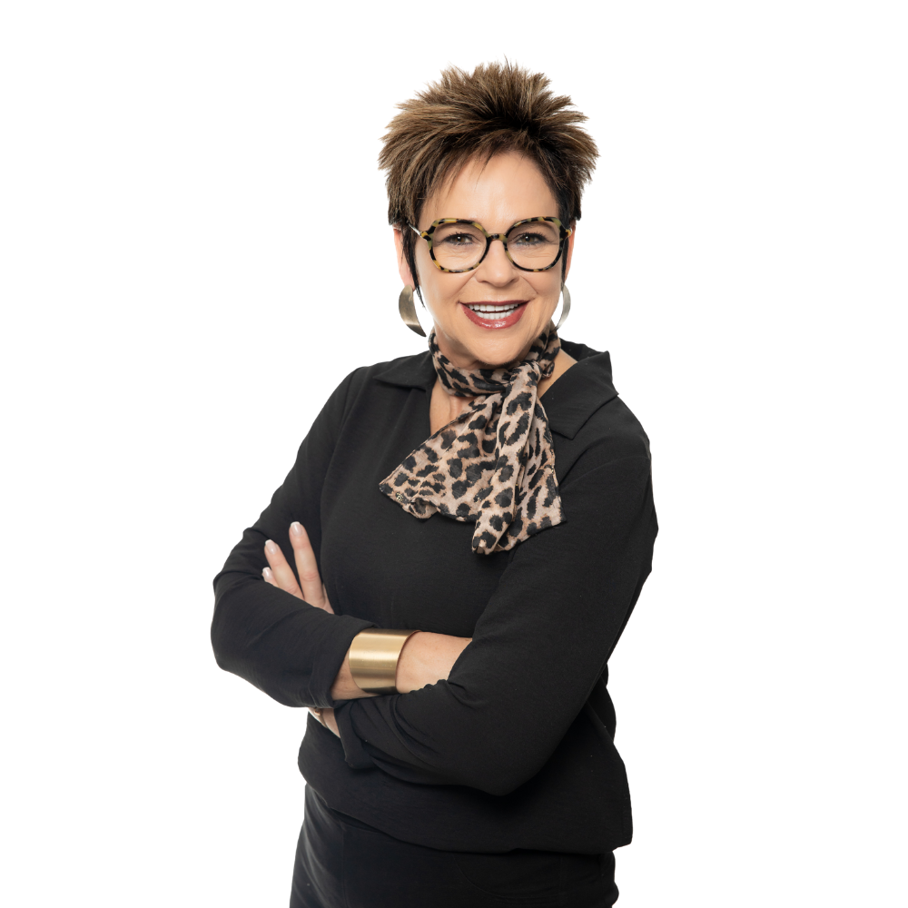 A person with short hair and glasses wearing a black shirt, leopard-print scarf