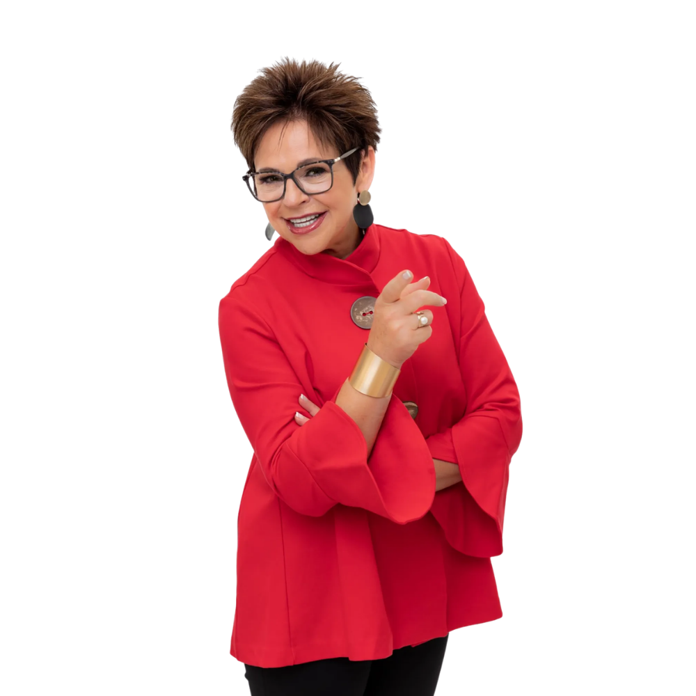 A person with short brown hair wearing glasses and a bright red jacket, smiling and pointing toward the camera.