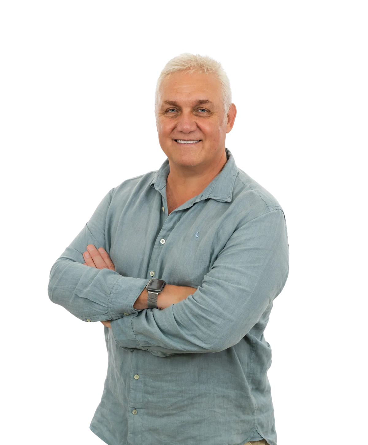 A smiling person wearing a blue button-down shirt with arms crossed, standing against a white background.