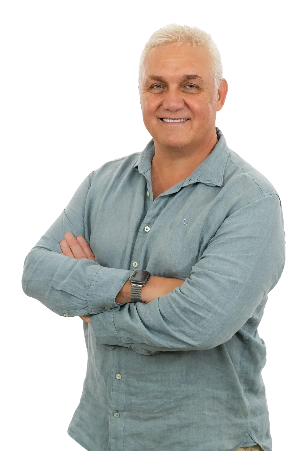 A smiling person wearing a blue button-down shirt with arms crossed, standing against a white background.