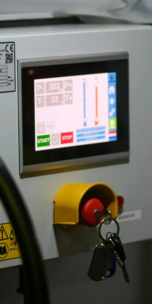Pannello di controllo industriale con touchscreen e pulsante di arresto di emergenza rosso.
